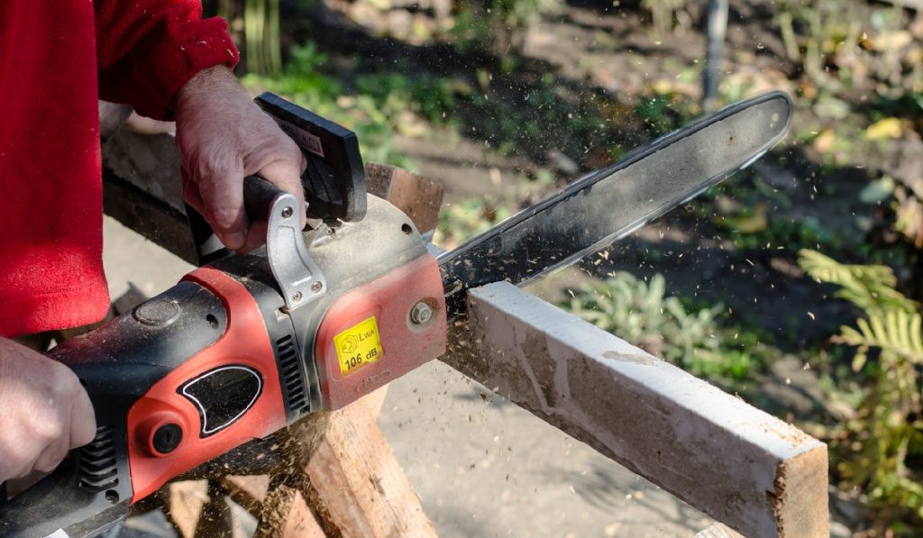 worker is sawing wood with a hand electric saw.