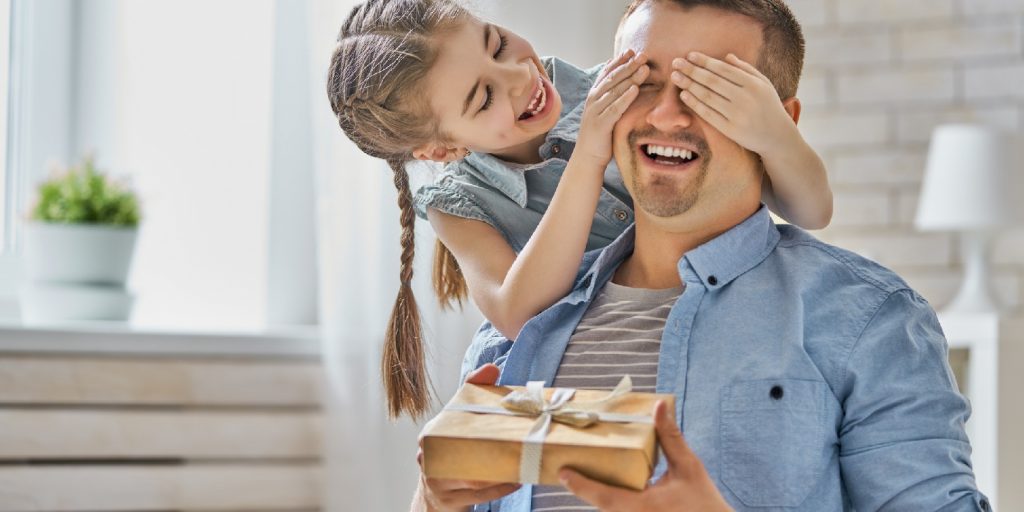 Happy father's day! Child daughter congratulating dad and giving him gift box