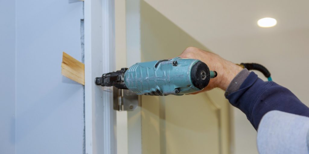 Worker with using air nail gun installing the interior door