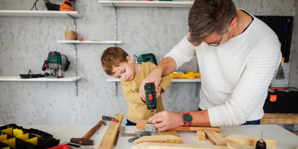 Father and son drilling wood in carpentry workshop