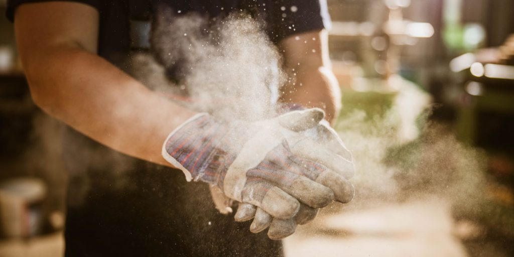 Close up of unrecognizable worker cleaning dust from his gloves.