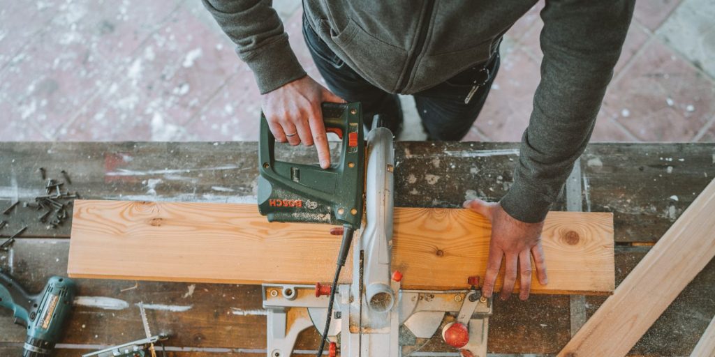 A Man Cutting Wood Using an Electric Jigsaw