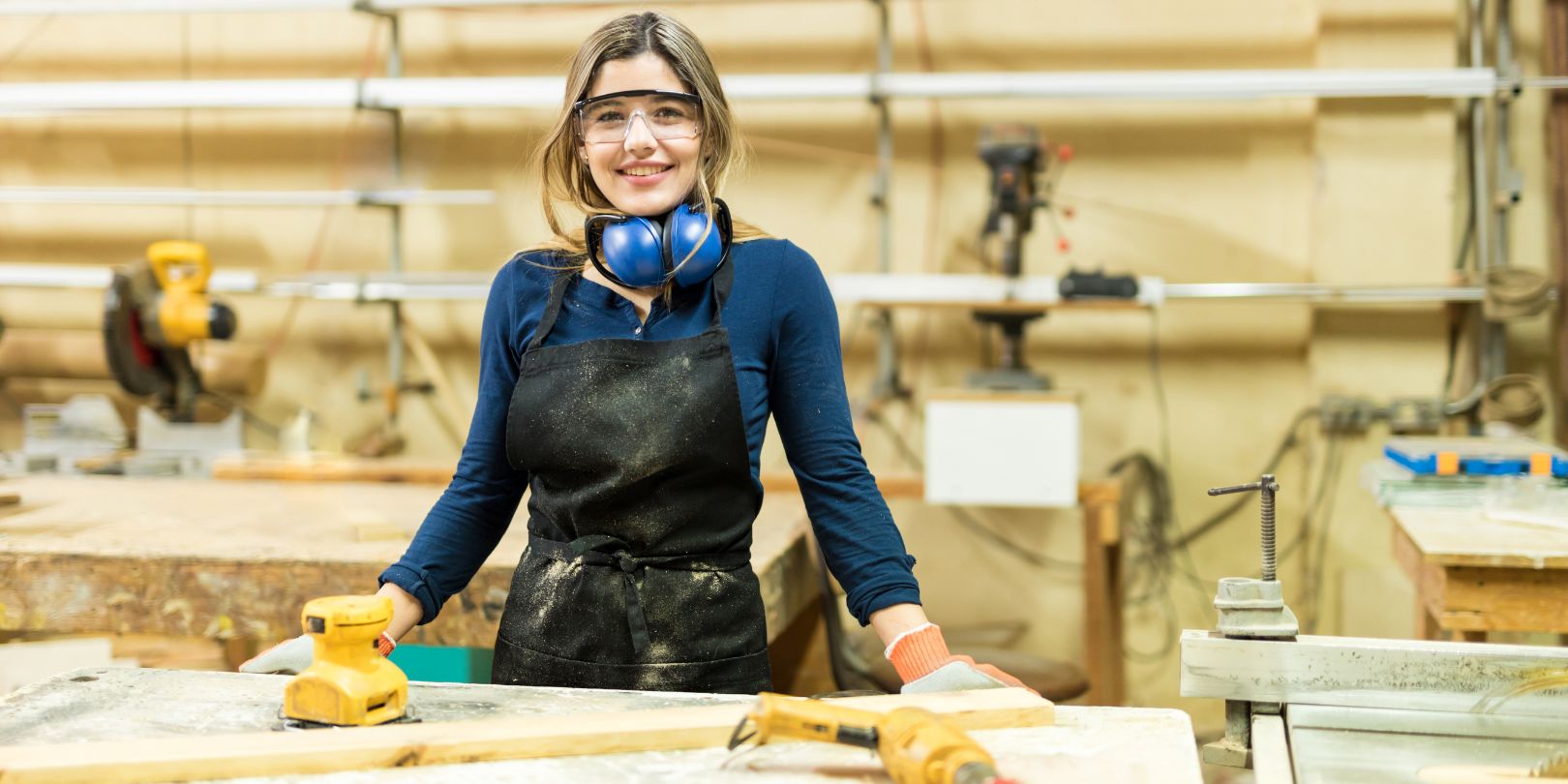 Portrait of a cute Hispanic female carpenter doing some work in a woodshop and smiling
