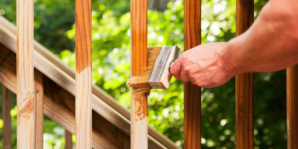 Hand with Paintbrush Staining Wood Deck Railing