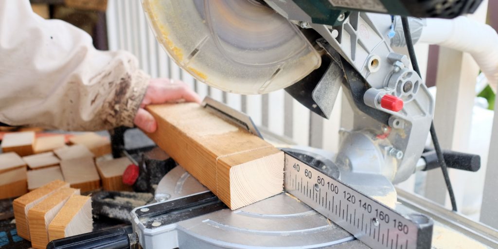 Only hends visible. Circular buzz saw cutting wooden plank. Woodwork