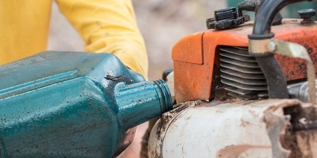 Thai worker filling oil to engine of chainsaw