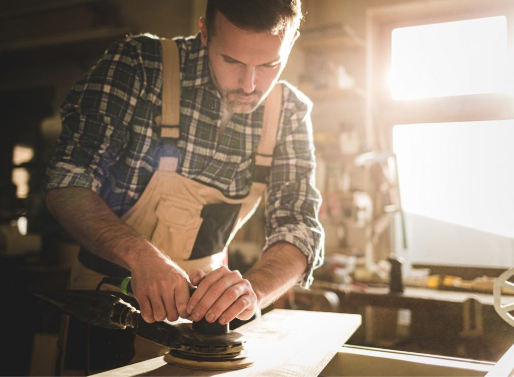 Man using an orbital sander on wood