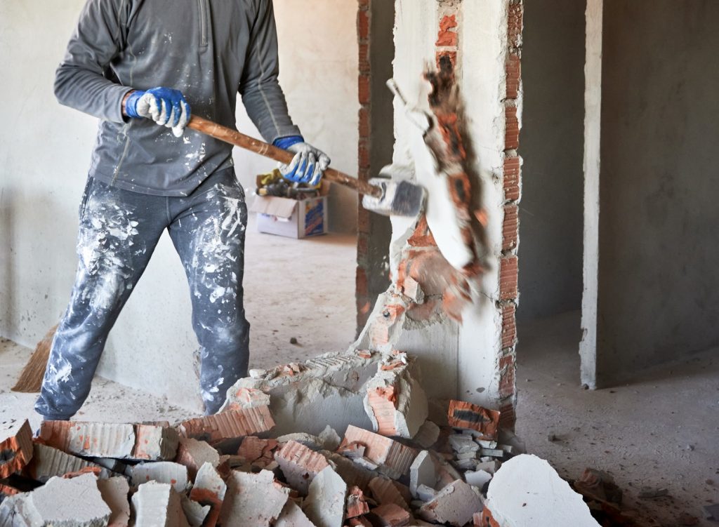 Man demolishing a wall with a sledgehammer